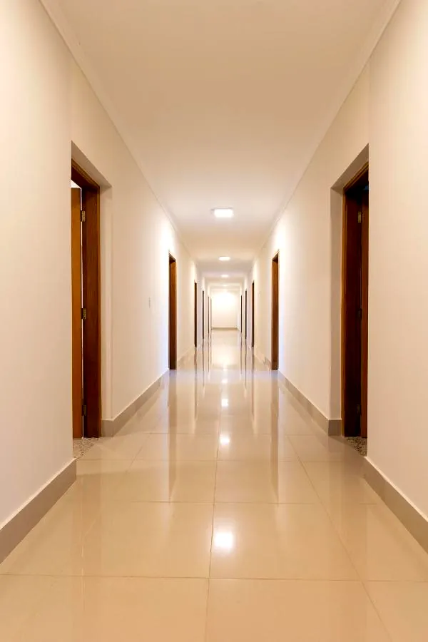 Corredor dos quartos com piso claro brilhante e portas de madeira