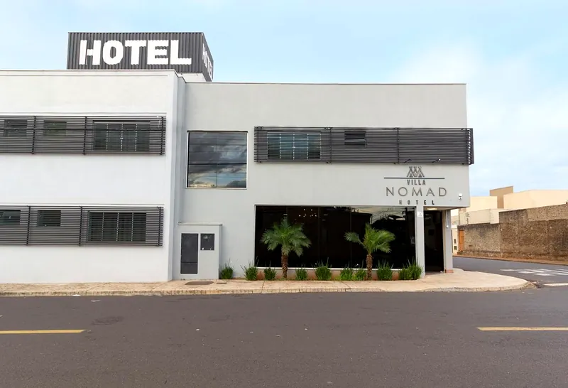 Fachada do hotel vista da rua, com o letreiro HOTEL e o logotipo na entrada