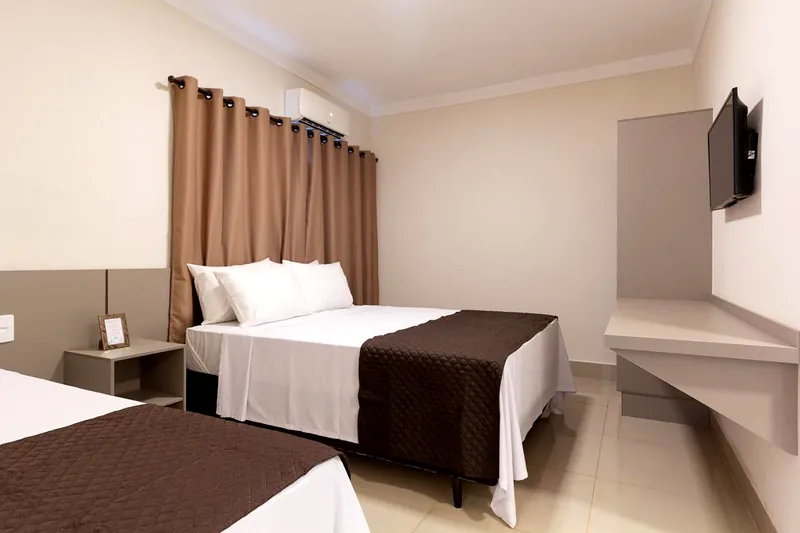 Quarto triplo com cama de casal, cama de solteiro e TV